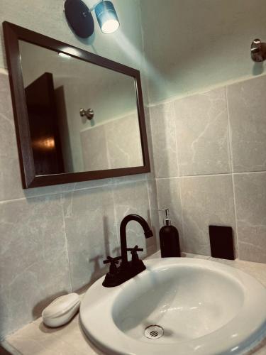 um lavatório de casa de banho com uma torneira e um espelho em Natural Black em Mérida