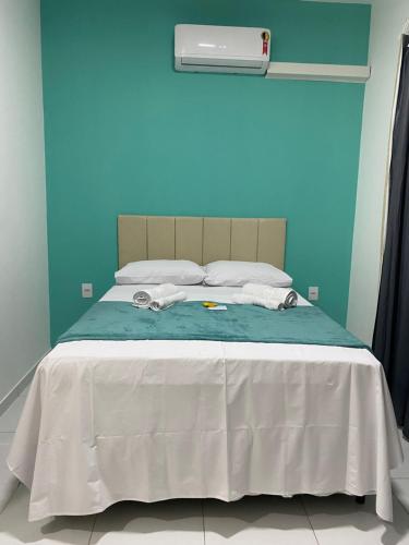a bed with a white blanket and a blue wall at Dunas Flat in Galinhos