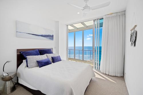 een witte slaapkamer met een bed en een groot raam bij Reflections Tower Two in Gold Coast