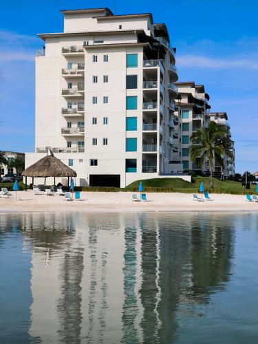 a hotel on a beach with chairs and a building at Playa Escondida: Confort y relax en el Caribe in María Grande