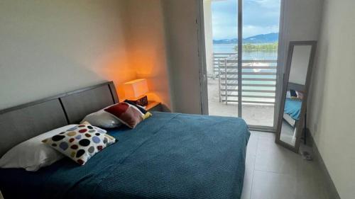 een slaapkamer met een blauw bed en een groot raam bij Playa Escondida: Confort y relax en el Caribe in María Grande