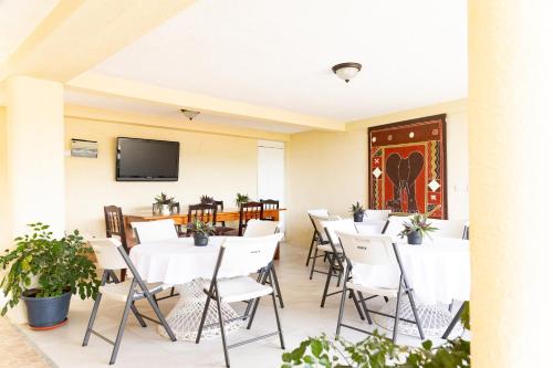 La Maison 29 في روسو: مطعم بطاولات بيضاء وكراسي وتلفزيون بشاشة مسطحة