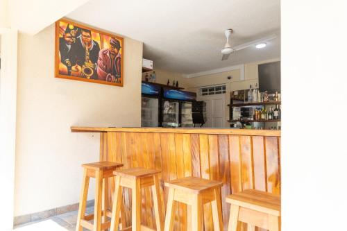 a bar with four wooden stools at a restaurant at La Maison 29 in Roseau