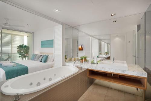 a large bathroom with a tub and a bed at Unit 105 Plantation Resort Rainbow Beach in Rainbow Beach