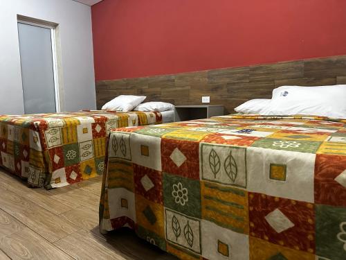 2 camas en una habitación con paredes rojas en Hotel Teresita en Puebla