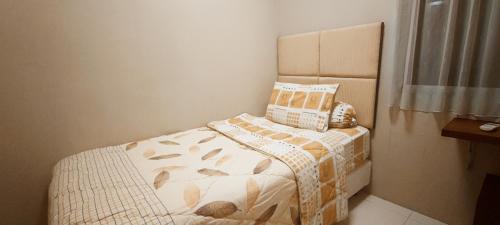 een kleine slaapkamer met een bed met een kussen erop bij Classy! 2BR Medit2 West Jakarta in Jakarta