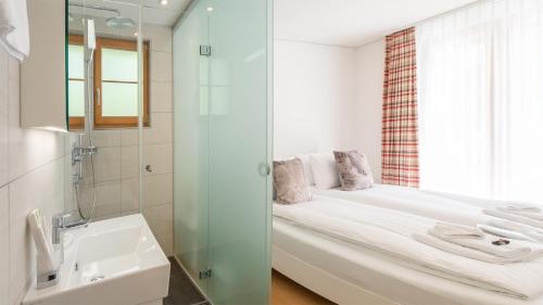 a bathroom with a bed and a shower and a sink at Panoramapark Soleil F Silbermond in Wengen
