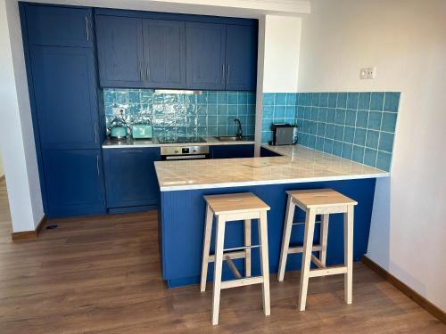 a blue kitchen with blue cabinets and two stools at Estrela Villas in Estrela
