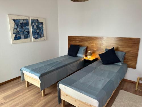 two beds in a room with blue pillows at Estrela Villas in Estrela