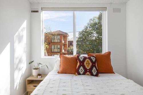 uma cama num quarto com uma grande janela em Dalgety Downtown - A Sunny St Kilda Beach Hideaway em Melbourne