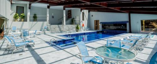 una piscina con sillas, una mesa y una piscina en Hotel Serrano Gramado - Apto Particular 452 en Gramado