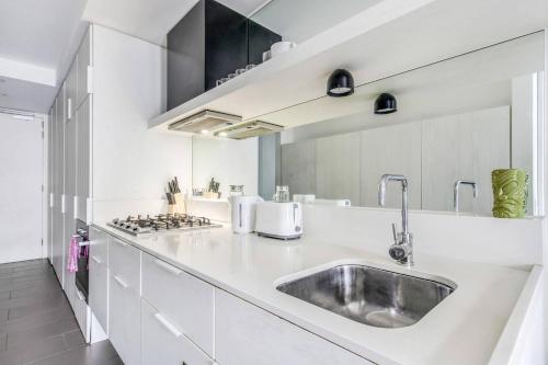 a kitchen with white counters and a sink at Experience Elegance at a Resort-style Urban Oasis in Melbourne