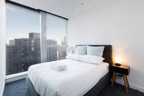 a bedroom with a white bed with a large window at Iconic High-view Oasis between Docklands and CBD in Melbourne