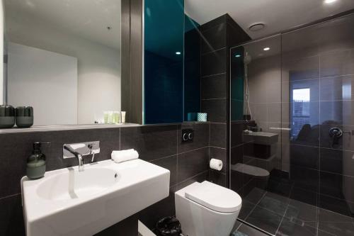 a bathroom with a sink and a toilet and a shower at Iconic High-view Oasis between Docklands and CBD in Melbourne