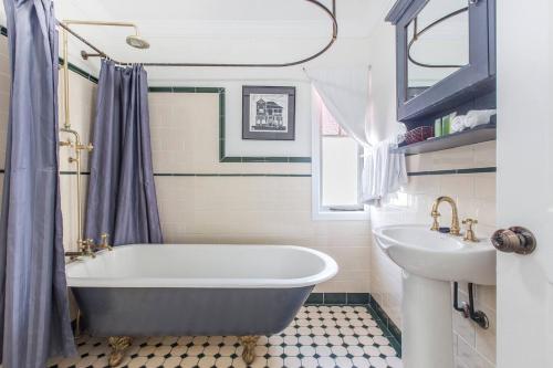 Fernberg Cottage - Sunny Queenslander Charm في بريزبين: حمام مع حوض ومغسلة