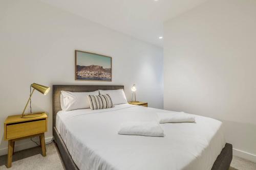 een slaapkamer met een groot wit bed en een nachtkastje bij The Nest in The West - Inner-city Sophistication in Melbourne