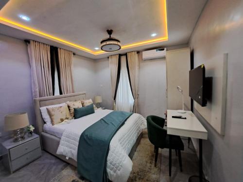 Schlafzimmer mit einem Bett, einem Schreibtisch und einem TV in der Unterkunft The Palladium Apartments in Ebute Lekki