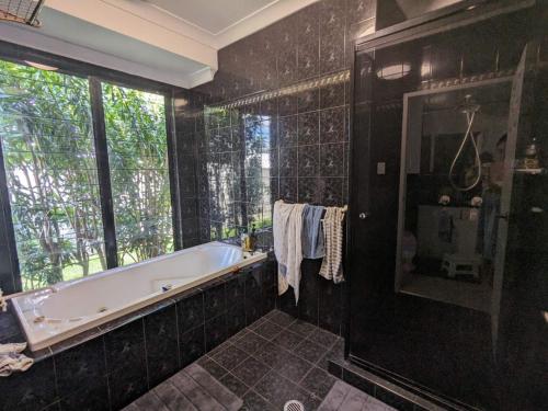 Baño negro con bañera y ventana en One bedroom in Mount Sheridan, en White Rock