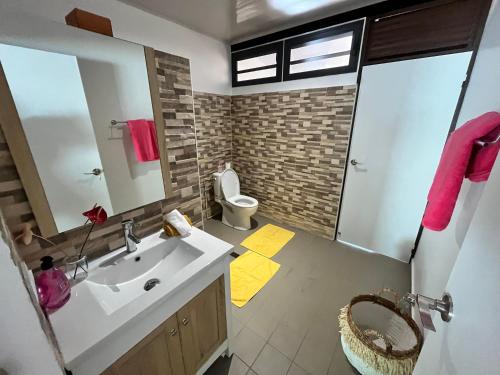 een badkamer met een wastafel, een toilet en een spiegel bij Tahiti - Kea Lodge in Papara