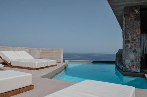 a pool with two beds and a view of the ocean at Mare e Pietra -Pietra Luxury Villa Pefkali in Pefkali