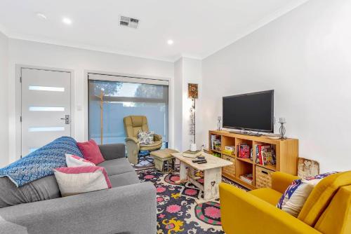 a living room with a couch and a tv at 'Christies Chic' A Family Getaway by the Beach in Adelaide