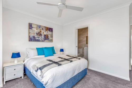 um quarto branco com uma cama e uma ventoinha de tecto em 'Christies Chic' A Family Getaway by the Beach em Christies Beach