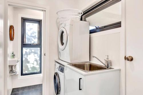 uma cozinha com um lavatório e uma máquina de lavar roupa em 'Christies Chic' A Family Getaway by the Beach em Christies Beach