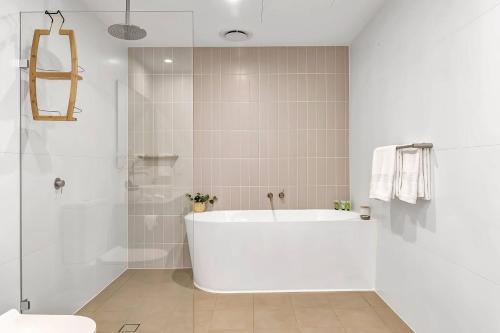 y baño blanco con bañera y ducha. en Hamptons-inspired Waterfront Living on Moana Beach, en Moana