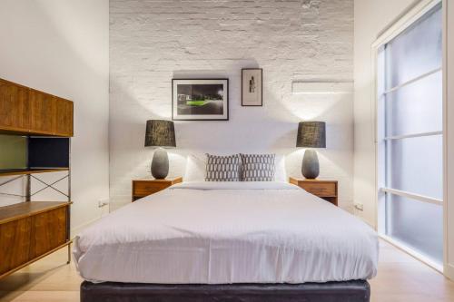 a bedroom with a large white bed and two lamps at Fitzroy Thrills in MacRobertson Factory Conversion in Melbourne