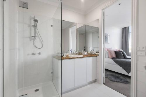 La salle de bains blanche est pourvue d'une douche et d'un lavabo. dans l'établissement Grand Luxury in the CBD along the Yarra River, à Melbourne