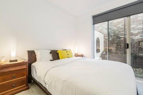 a bedroom with a white bed and a large window at 'The Courtyard Chateau' Fresh and Modern off Toorak Rd in Melbourne