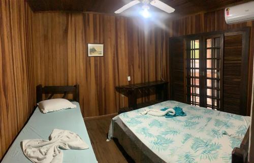 two beds in a room with wooden walls at Pousada D'Aconchego Nova Brasilia in Ilha do Mel