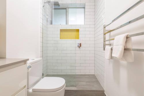a white bathroom with a toilet and a window at 'The Courtyard Chateau' Fresh and Modern off Toorak Rd in Melbourne