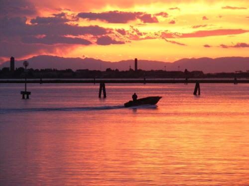 a man in a boat in the water at sunset at Hotel Il Lato Azzurro - Isola di Sant'Erasmo - NO VEHICLES ACCESS in Venice