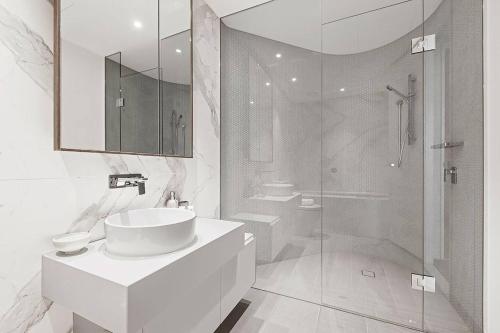 a white bathroom with a sink and a shower at Top of Town - Penthouse with Every Opulence in Melbourne