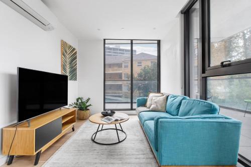 a living room with a blue couch and a flat screen tv at Executive Resort-Style Living at Leafy Albert Park in Melbourne