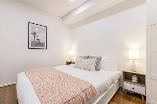 a white bedroom with a bed and two lamps at Nottville Poolside - Coastal Cosmopolitan off Bay St in Melbourne