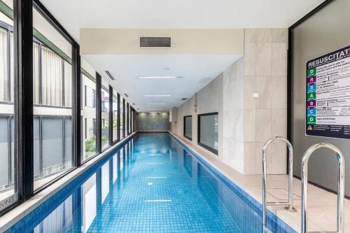 a swimming pool in a building with windows at Nottville Poolside - Coastal Cosmopolitan off Bay St in Melbourne