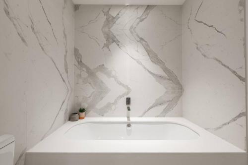 a bath tub in a bathroom with a marble wall at Experience Lakeside Luxury from Three Balconies in Melbourne