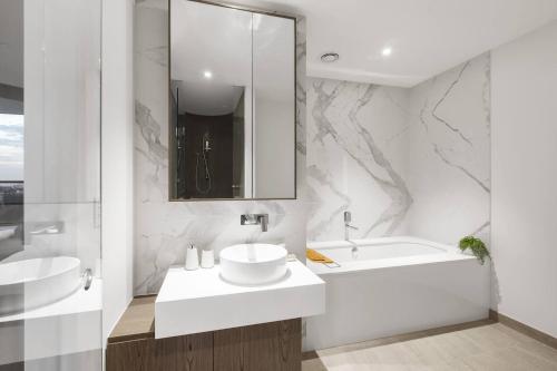 a white bathroom with a sink and a bath tub at Lakeside Five Star Luxury with Uninterrupted Views in Melbourne