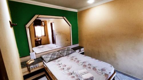 a small bedroom with a bed and a mirror at Grande Hotel in Duque de Caxias