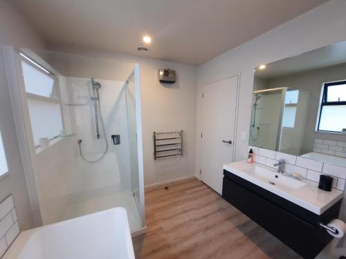 a white bathroom with a sink and a shower at Colour on Cairnmuir in Wanaka