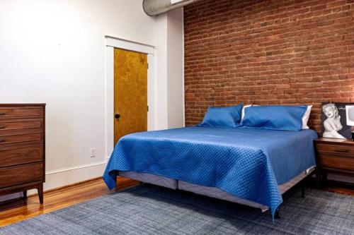 a bedroom with a blue bed and a brick wall at The 611 Loft. Central Downtown Location. in Roanoke