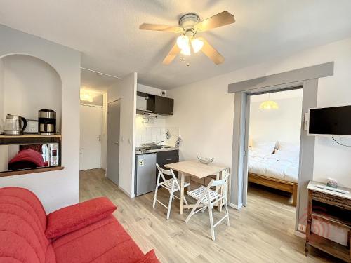 un salon avec un canapé rouge et une table dans l'établissement Appartement F2 avec balcon, proche des Thermes à Lamalou-les-Bains, Animaux Acceptés, Parking Gratuit - FR-1-451-166, à Lamalou-les-Bains