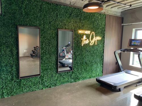 a gym with a green wall with mirrors and a treadmill at Luxury Furnished Apartment in Heart of Quincy in Quincy