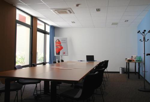 a conference room with a large wooden table and chairs at ibis Lille Centre Grand Palais in Lille