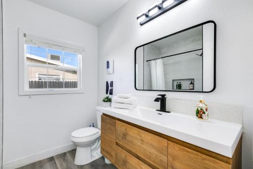 a bathroom with a sink and a toilet and a mirror at Modern Home - Family Fun Hub - Getaway - Billiards By Zen Living Short Term Rental in Glendora