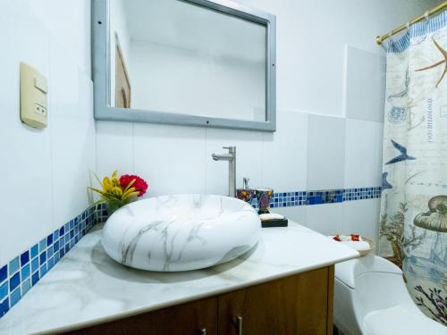 EXCLUSIVE CONDO GALAPAGOS & BEYOND 2 في بويرتو أيورا: حمام مع حوض أبيض كبير على منضدة