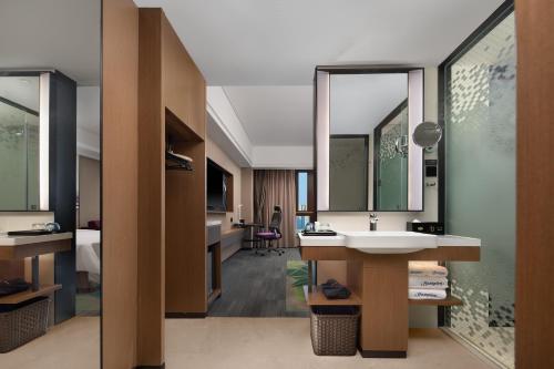 広州市にあるHampton by Hilton Guangzhou Luoxiのホテルルーム(シンク付)とベッドルーム1室が備わります。