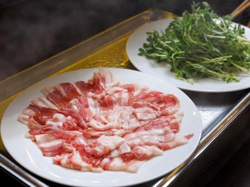 two plates of bacon and greens on a tray at JR Kyushu Hotel Kagoshima in Kagoshima